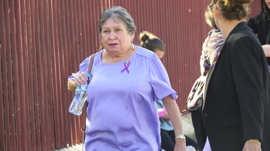 A woman in a purple shirt walking.