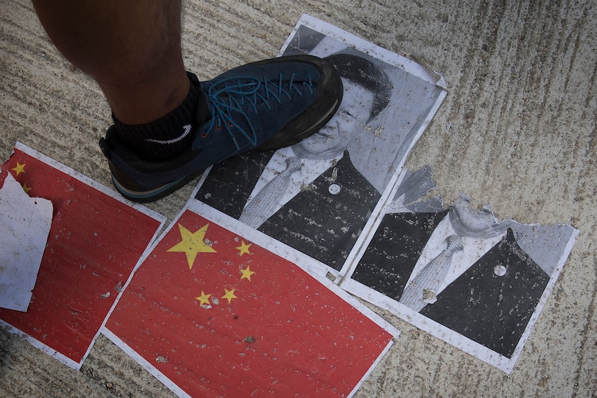 Protesters walk on an image of Chinese President Xi Jinping.