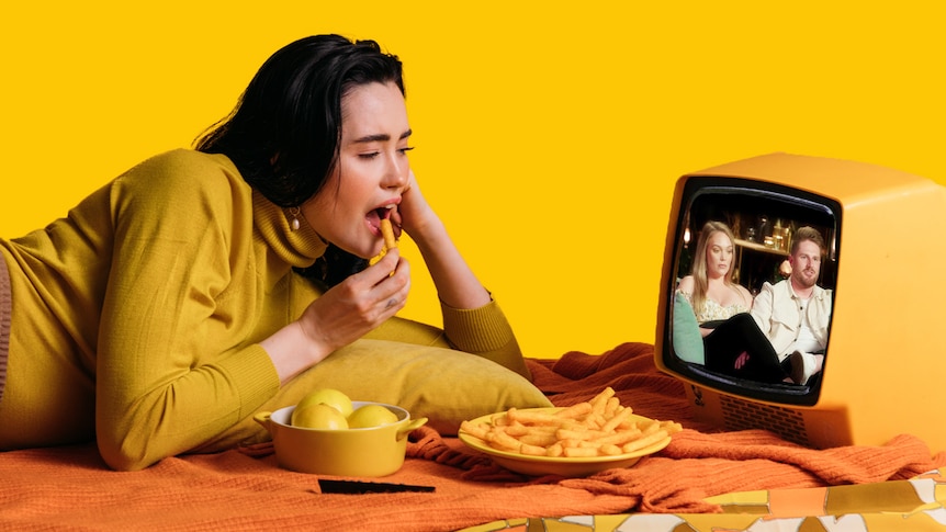A woman eats chips while watching Married at First Sight on a small TV.