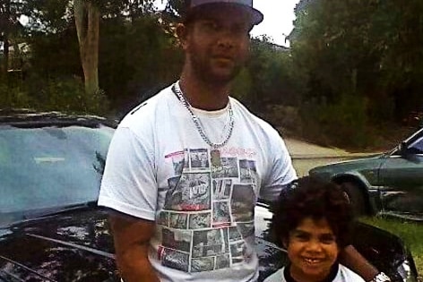 Sam May stands against a car with his arm around Cassius Turvey, then a young boy.