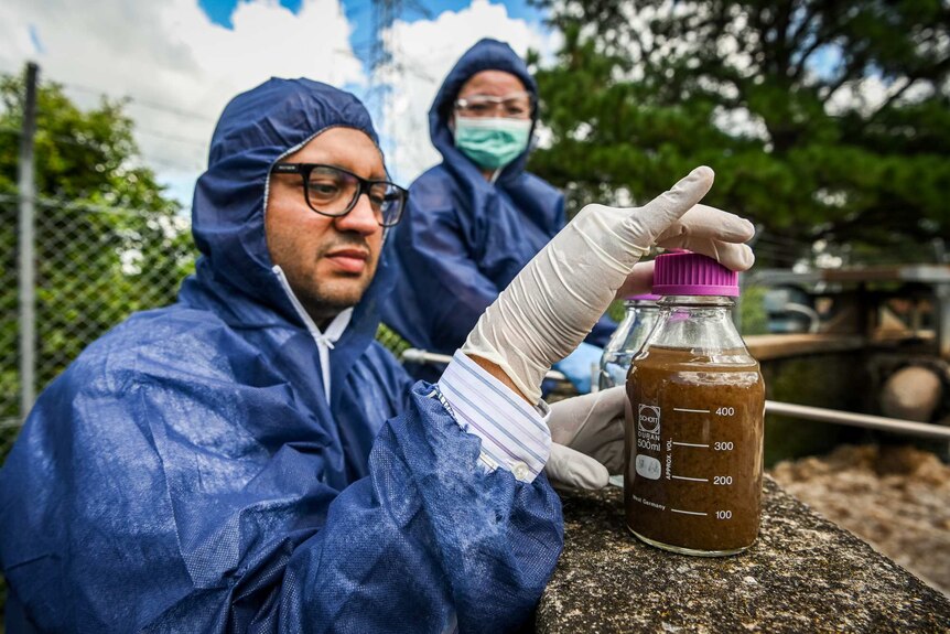 Ali Khalid seals a jar with a sewage sample inside.