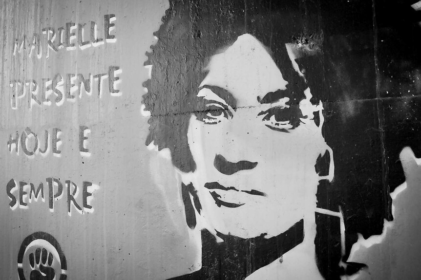 A black, grey and white mural shows a stencil of a woman's head next to some text