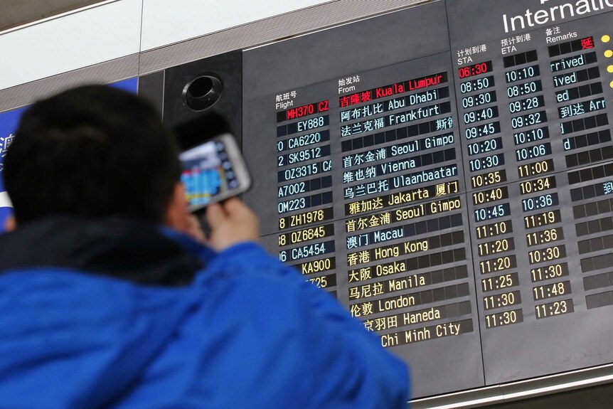 Man takes photos of flight information board at Beijing Capital International Airport