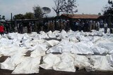 UN Peacekeepers and medics stand beside the bagged bodies of victims of an oil tanker explosion