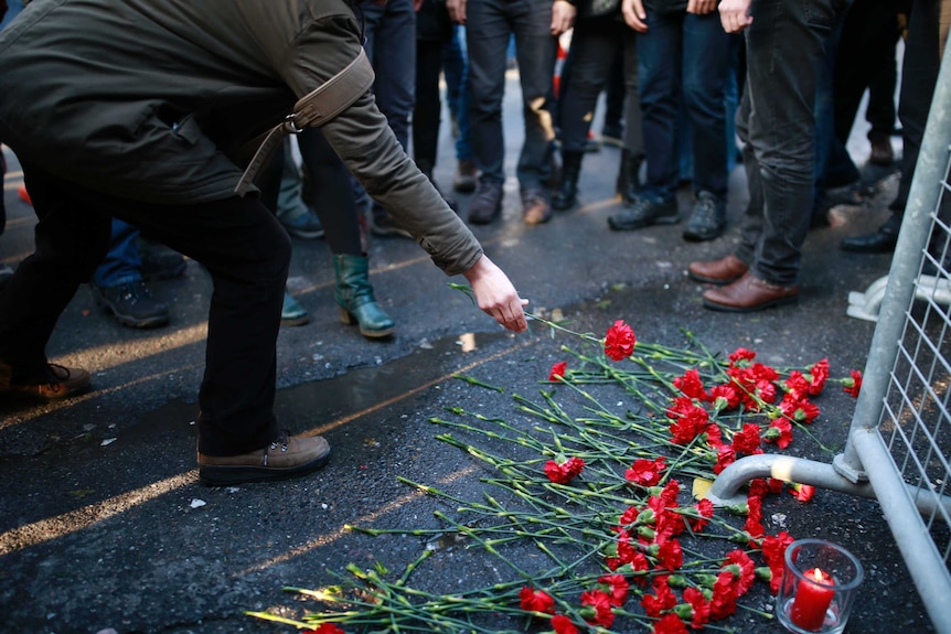 People leave flowers for the victims outside a nightclub which was attacked by a gunman overnight in Istanbul