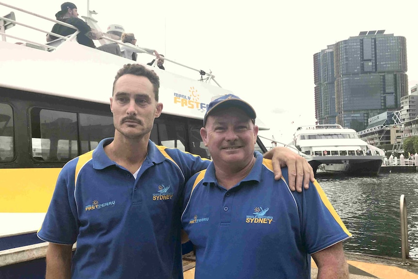 Two men standing in front of a ferry.
