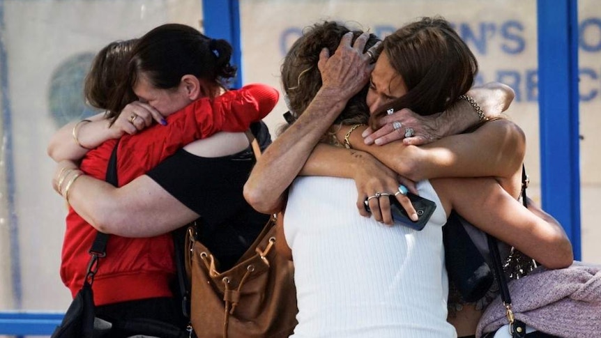 A distraught Lacey Harrison receives a hug from a family member outside Princess Margaret Hospital.