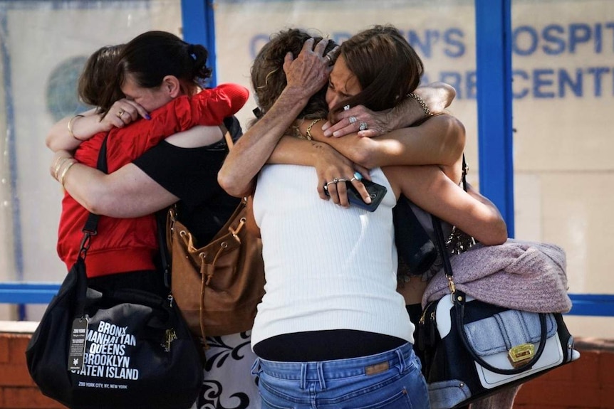 A distraught Lacey Harrison receives a hug from a family member outside Princess Margaret Hospital.