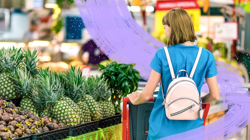 A woman pushes a shopping trolley past a display of fresh pineapples, adding to her incidental exercise.