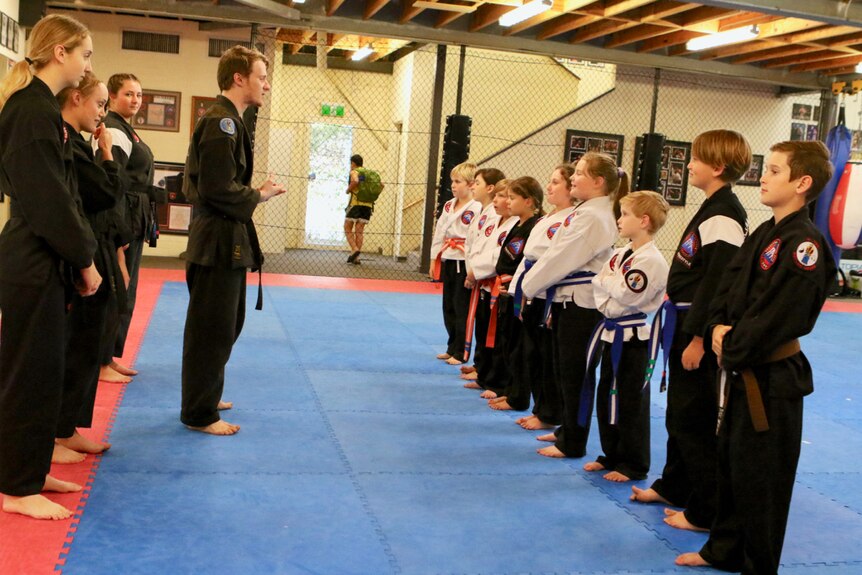 Kickboxing instructor Sam Gaynor stands in front students in a studio.