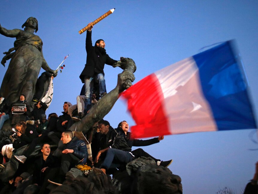 A man holds a giant pencil as part of a solidarity with Charlie Hebdo rally.