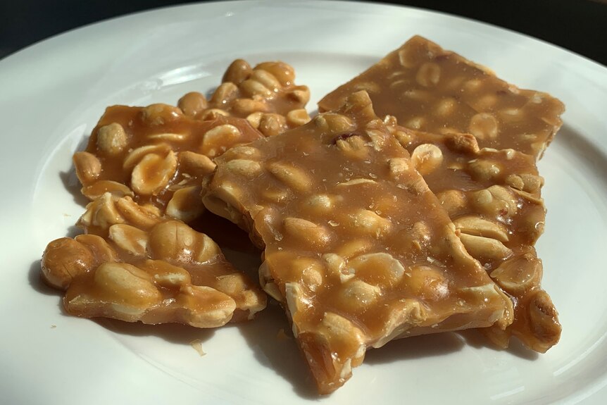 Large shards of peanut brittle on a white plate.