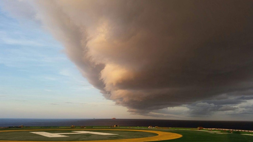 Whirling storm front coming toward oil and gas rig with helicopter pad in foreground