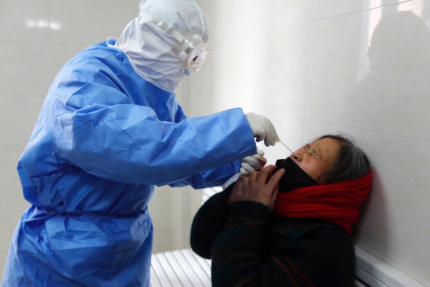 A doctor takes a swab from a woman to test for coronavirus.