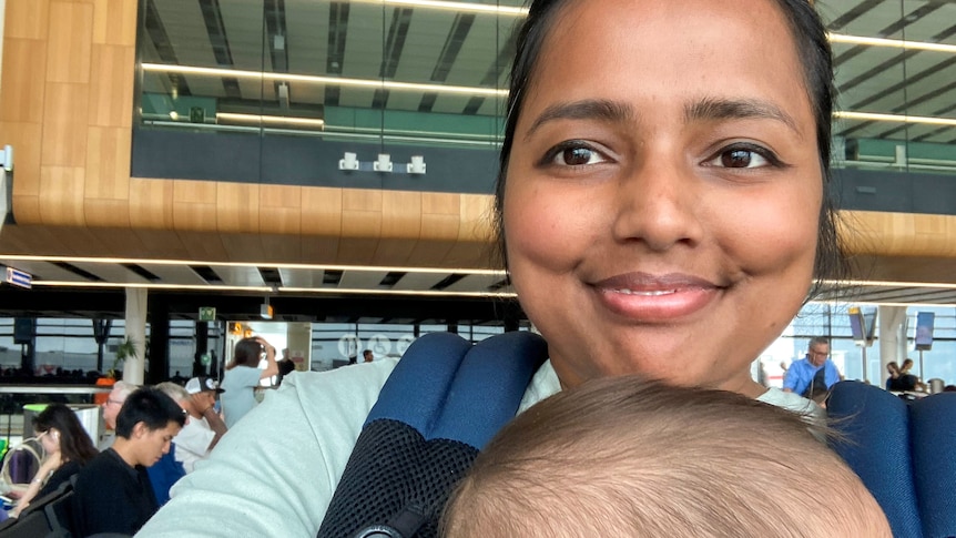 A smiling mum with a young baby in a baby carrier 