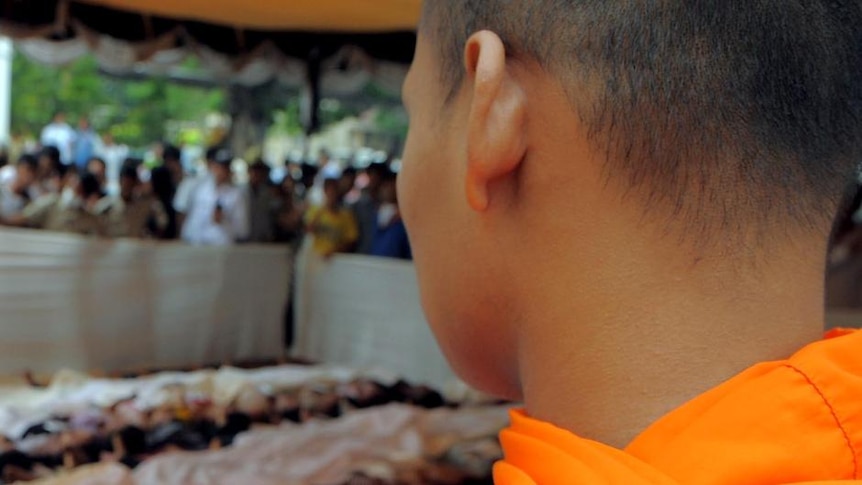 Cambodian Buddhist monks look at bodies lined up on the ground at a hospital in Phnom Penh