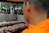 Cambodian Buddhist monks look at bodies lined up on the ground at a hospital in Phnom Penh