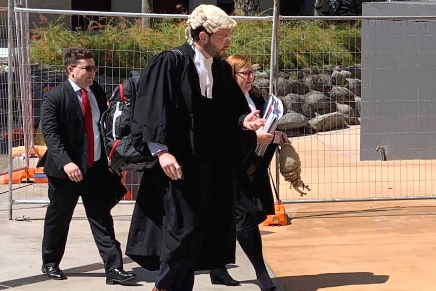 A crown prosecutor in a legal wig walking into a courthouse