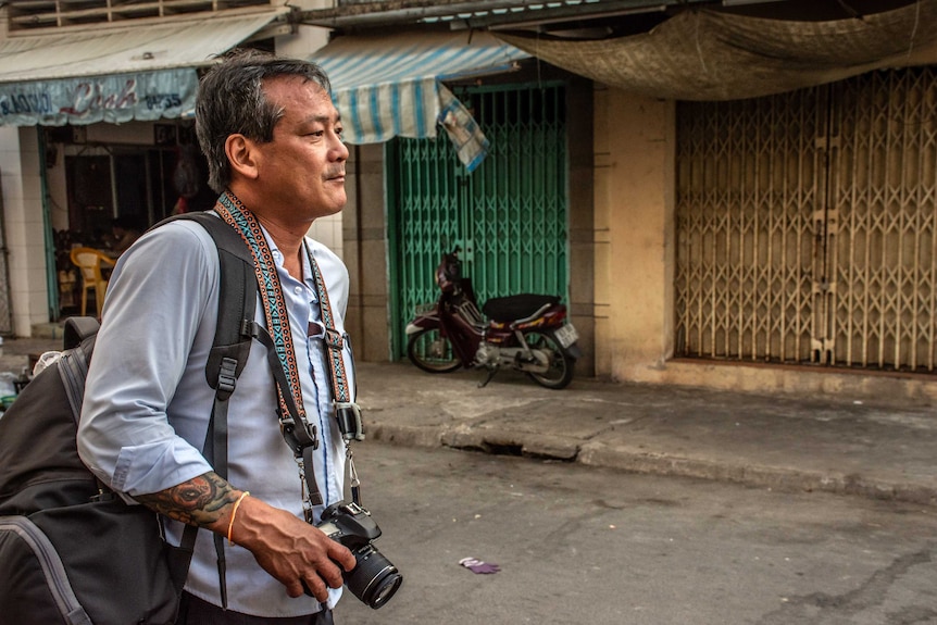 Mike in the street looking pensive with a camera