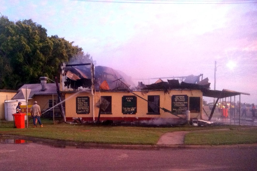 The remains of the Burketown pub are hosed down after it was gutted by fire.