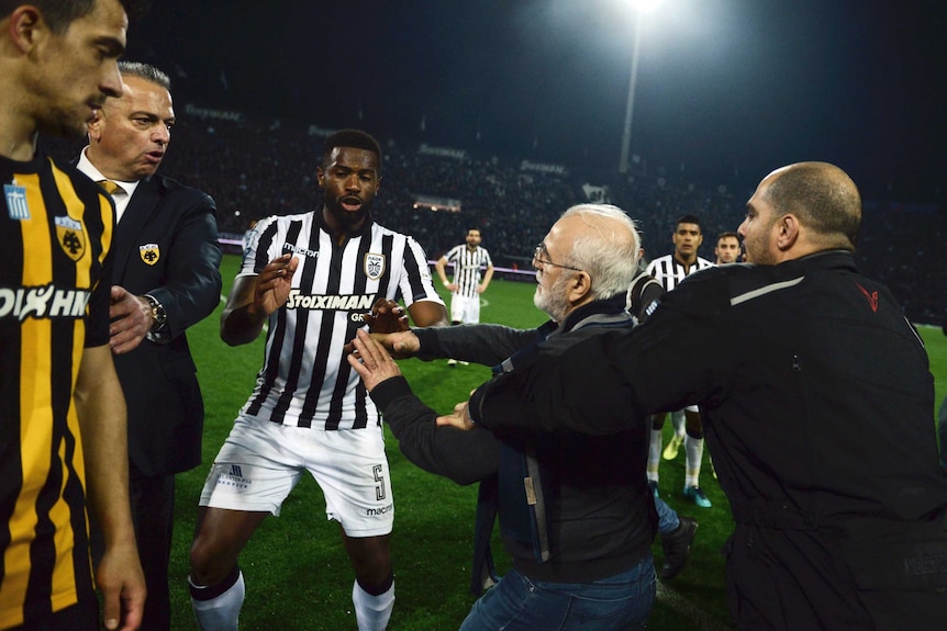 A bodyguard tries to hold Ivan Savvidis back as he approaches another person on the soccer pitch.