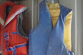 A red life jacket and blue life jacket hanging up.