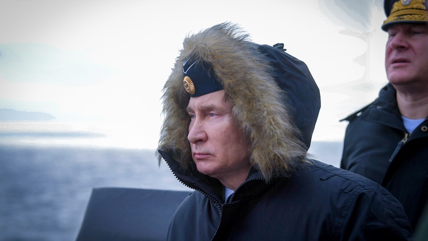 Vladimir Putin looking downcast while wearing a fur trimmed hooded coat at sea