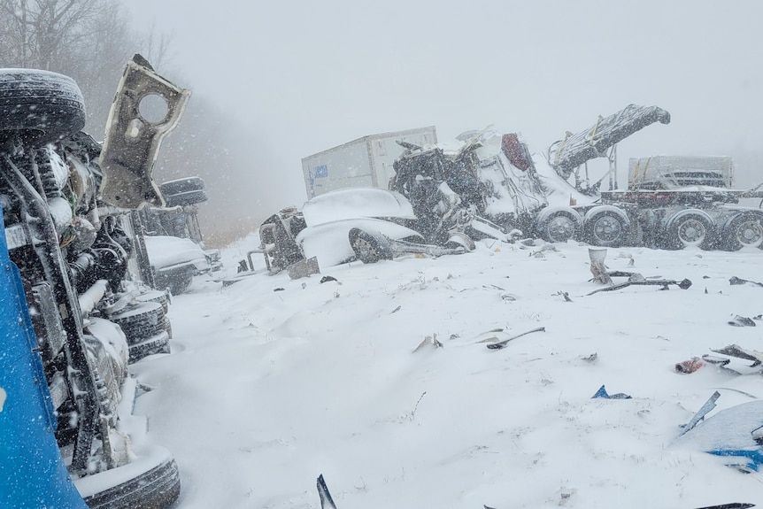 A pile of damaged cars in the snow