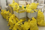 Yellow bags saying 'contaminated' lie on the ground of a lab.