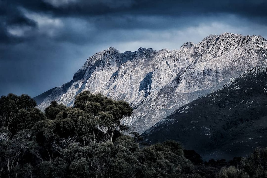 Mountainous range with dark clouds overhead.