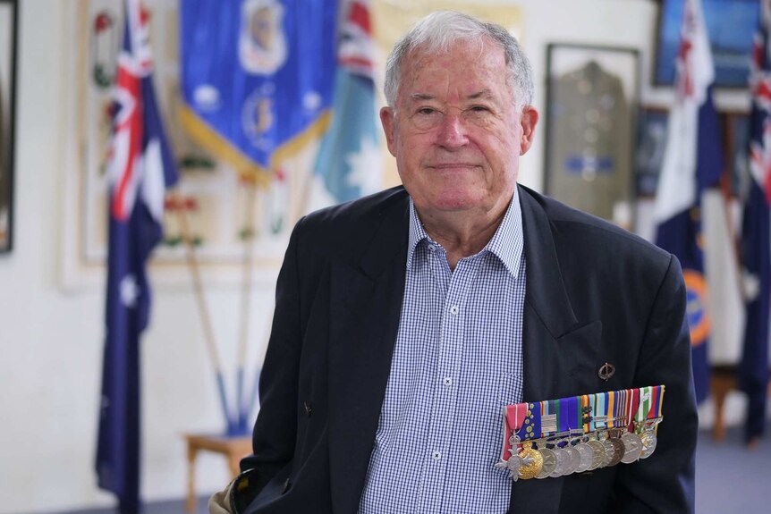 Laurie Fisher, wearing his medals, in front of a military display at the Albany RSL Club.