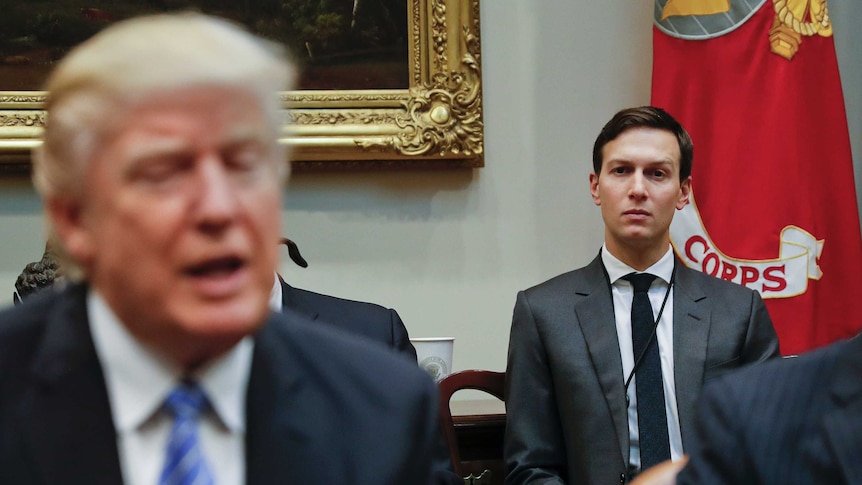 Jared Kushner sits behind his father-in-law Donald Trump, who is out of focus.