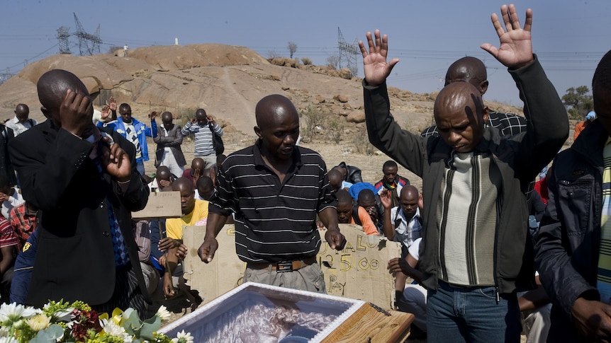 A man raises his hands to pray over the coffin containing the body of Mpuzeni Ngxande, one of the 34 striking miners that were killed by police on August 16.