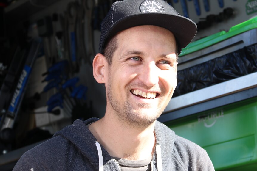 A close up of a mechanic wearing a cap and smiling