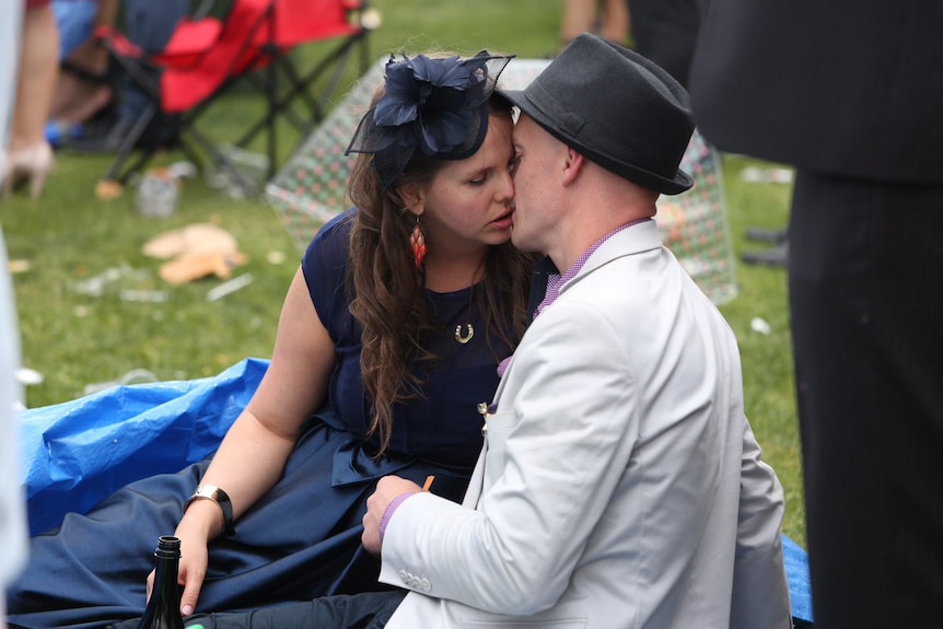 Man and woman sit on the ground kissing