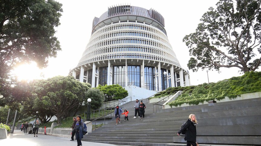 Pedestrians walk past The Beehive, New Zealand's Parliament building.