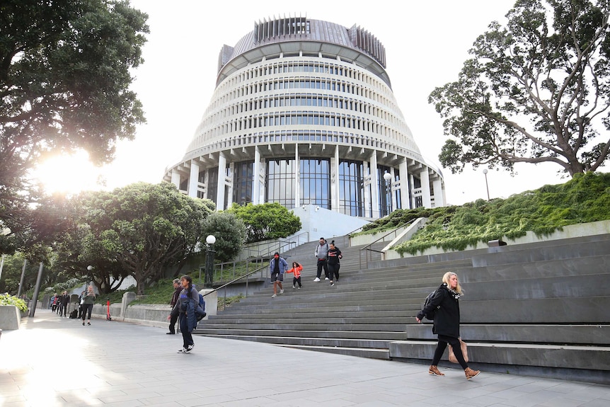 Pedestrians walk past The Beehive, New Zealand's Parliament building.