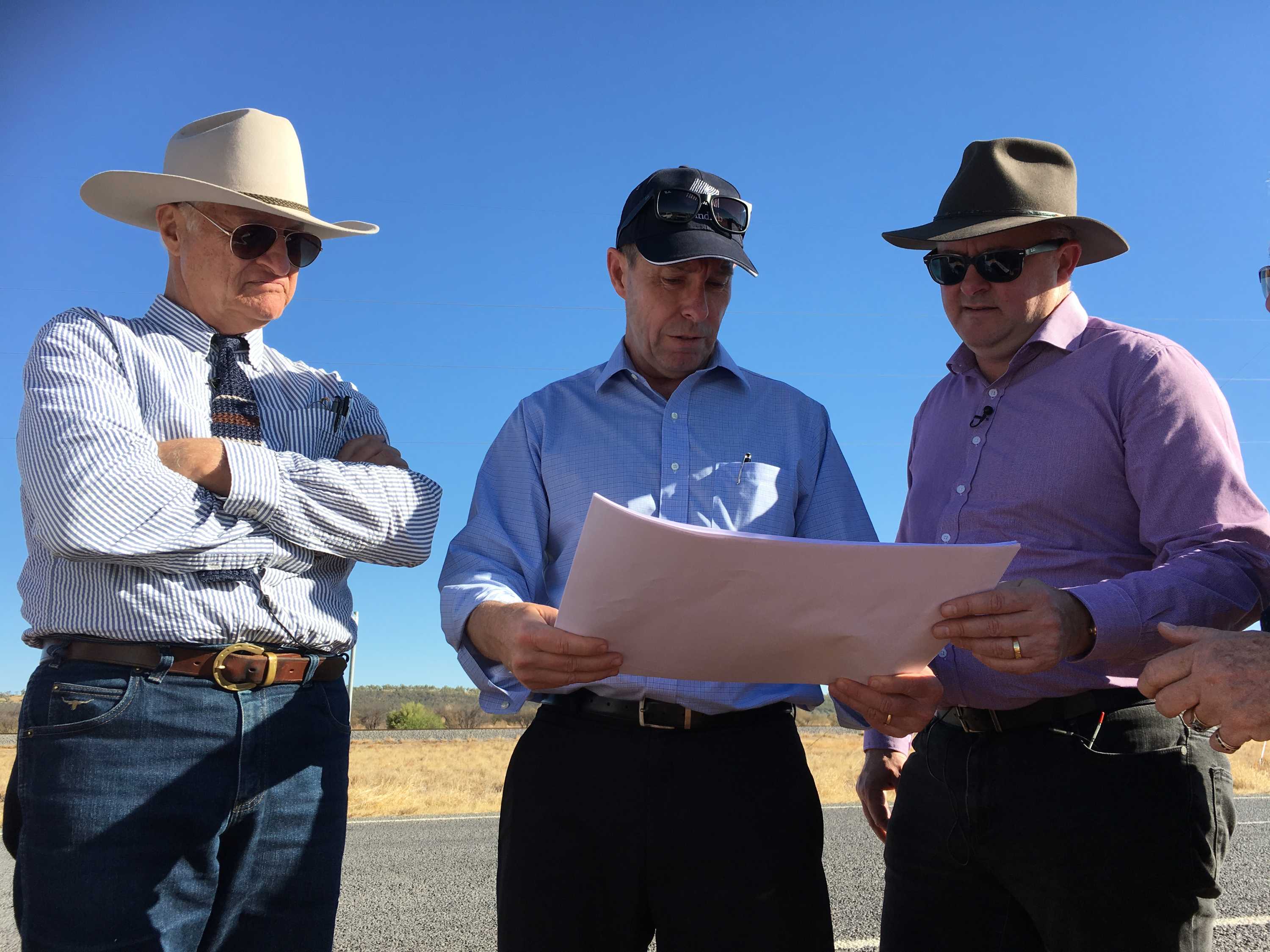 Bob Katter, Anthony Albanese and Windlab's Roger Price stand around looking at a map.
