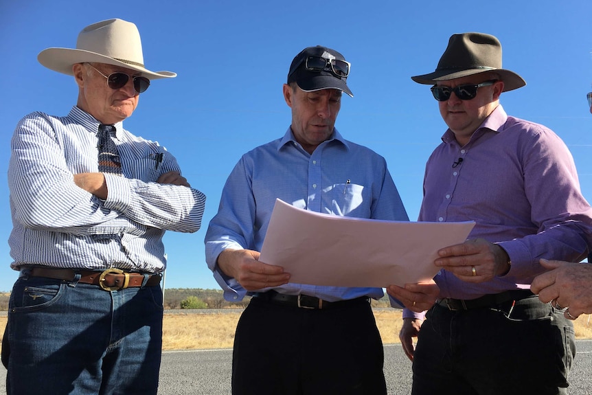 Bob Katter, Anthony Albanese and Windlab's Roger Price stand around looking at a map.