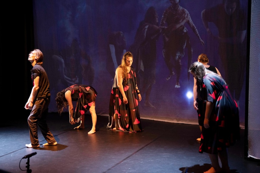 A group of dancers moves around a stage