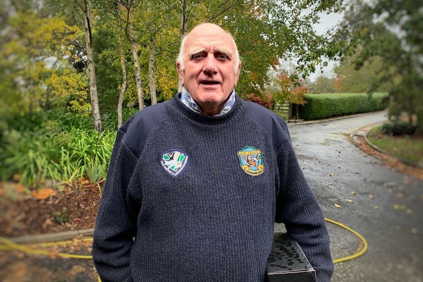 A man standing in front of trees looking directly into the camera