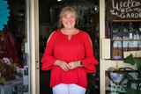 Giftshop owner Liz Austin stands in the doorway of her gift store in Coolah in New South Wales with colourful merchandise