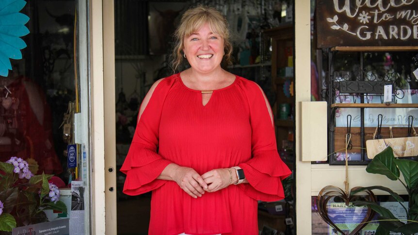 Giftshop owner Liz Austin stands in the doorway of her gift store in Coolah in New South Wales with colourful merchandise