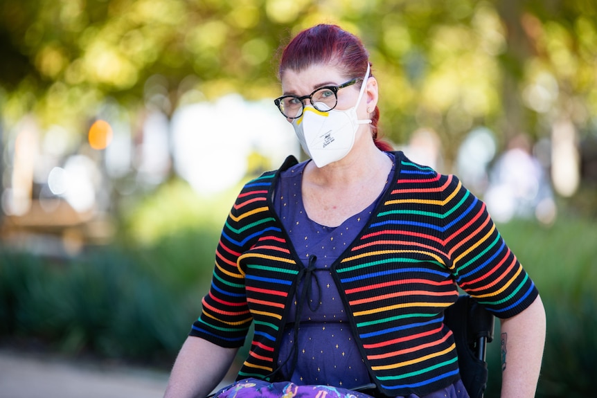 Sam Connor wearing a COVID mask and a colourful, striped cardigan.