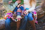 Parents cuddle a child sitting in their lap.