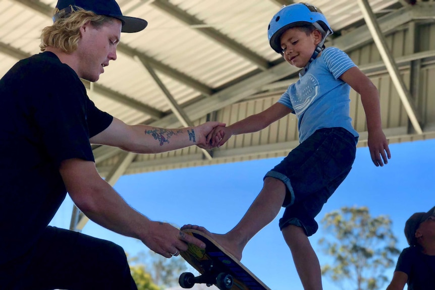 Child in Murgon, Queensland, being taught how to skateboard.