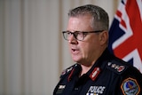 NT Police Commissioner Jamie Chalker is talking in front of a microphone. He looks serious.