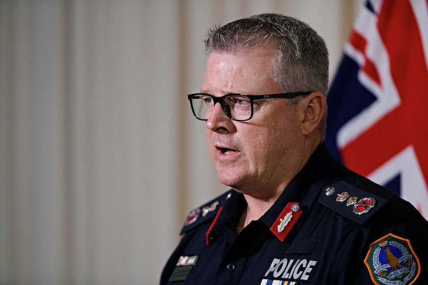 NT Police Commissioner Jamie Chalker is talking in front of a microphone. He looks serious.