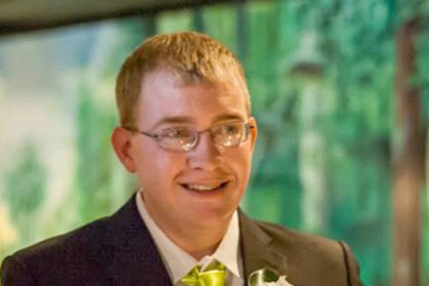 Brian Earl Johnston wears glasses and a suit, smiling.