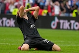 Thomas Mueller on his knees with his head in his hands. 